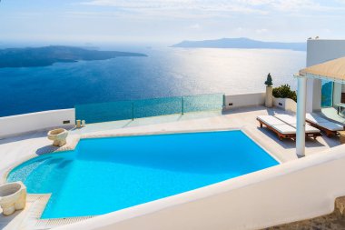 Yunanistan 'ın Santorini adasındaki Imerovigli köyünün tipik beyaz mimarisi Caldera manzarası ve ön planda yüzme havuzu.