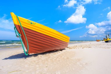 Kumlu Baltık Denizi sahilinde renkli bir balıkçı teknesi, Polonya