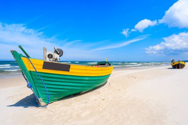 Kumlu Baltık Denizi sahilinde renkli bir balıkçı teknesi, Polonya