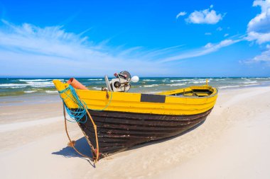 Kumlu Baltık Denizi sahilinde renkli bir balıkçı teknesi, Polonya