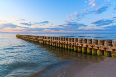 Leba sahilinde, Baltık Denizi 'nde, Polonya' da, ön planda ahşap dalgalarla gün batımı