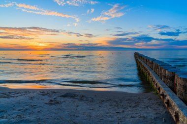 Leba sahilinde, Baltık Denizi 'nde, Polonya' da, ön planda ahşap dalgalarla gün batımı