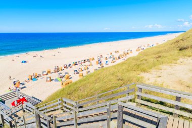 Kuzey Denizi kıyısında tahta yol ve Almanya 'nın Sylt Adası' ndaki Wenningstedt köyü yakınlarındaki güzel plaj manzarası.