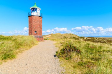 Kum tepesindeki deniz feneri mavi gökyüzüne karşı, Almanya 'nın Kampen köyü yakınlarındaki Sylt adasının kuzey sahilinde beyaz bulutlar.
