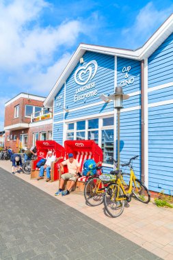 SYLT Adaları, GERMANY - SEP 6, 2016: Almanya 'nın Sylt adasının kuzey kıyısındaki List limanında mağazaları bulunan tipik mavi binanın önündeki plaj sandalyelerinde dinlenen insanlar.