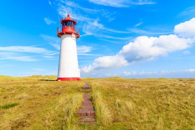 Kum tepeciklerindeki Ellenbogen deniz feneri, Almanya 'nın Sylt adasının kuzey kıyısında beyaz bulutlu mavi gökyüzüne karşı.