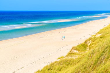 Almanya 'nın Sylt Adası' ndaki Rantum ve Hornum köyleri arasında cennet gibi plajlarda yürüyen bir çift insan.