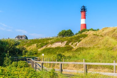 Almanya 'nın Sylt Adası' nın güney kıyısındaki Hornum köyünde kumdaki deniz fenerine karşı mavi gökyüzü.