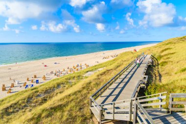 Kuzey Denizi kıyısında tahta yol ve Almanya 'nın Sylt Adası' ndaki Wenningstedt köyü yakınlarındaki güzel plaj manzarası.
