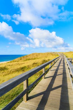 Kuzey Denizi kıyısında tahta yol ve Almanya 'nın Sylt Adası' ndaki Wenningstedt köyü yakınlarındaki güzel plaj manzarası.