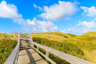 Kuzey Denizi kıyısında tahta yol ve Almanya 'nın Sylt Adası' ndaki Wenningstedt köyü yakınlarındaki güzel plaj manzarası.