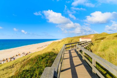 Kuzey Denizi kıyısında tahta yol ve Almanya 'nın Sylt Adası' ndaki Wenningstedt köyü yakınlarındaki güzel plaj manzarası.