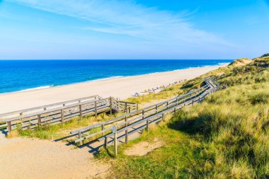 Kuzey Denizi kıyısında tahta yol ve Almanya 'nın Sylt Adası' ndaki Wenningstedt köyü yakınlarındaki güzel plaj manzarası.