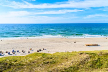 Almanya 'nın Sylt Adası' ndaki Wenningstedt köyü yakınlarında kumsalda sandalyeleri olan güzel bir sahil manzarası.