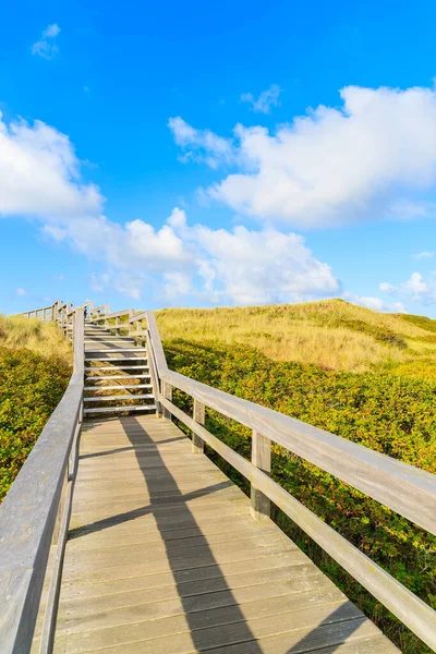 Kuzey Denizi kıyısında tahta yol ve Almanya 'nın Sylt Adası' ndaki Wenningstedt köyü yakınlarındaki güzel plaj manzarası.