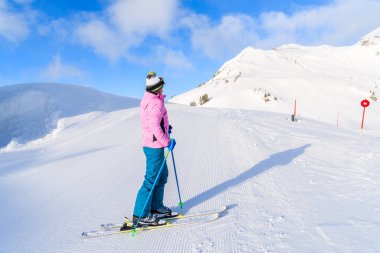 Genç bayan kayakçı Avusturya 'nın Obertauern kayak alanındaki dağlara bakıyor.