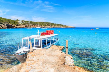 İspanya 'nın İbiza adasındaki Cala Portinatx Körfezi' nde demirleyen turistler için beyaz ve mavi feribot.