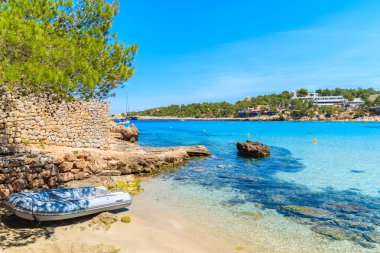 Ibiza adası, İbiza 'da, sığ kristal berrak deniz suyuyla huzurlu Cala Portinatx plajındaki sandal.