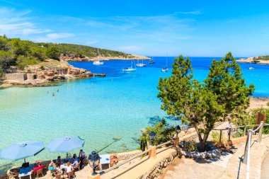 CALA PORTINATX BAY, IBIZA ADASI - 16 Mayıs 2017: İspanya 'nın İbiza adasındaki Cala Portinatx Körfezi kıyısındaki restoranda oturan insanlar.