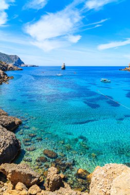 İspanya 'nın İbiza adasında mavi deniz suyunda tekneli Cala Benirras Körfezi manzarası