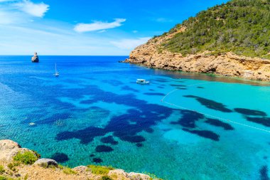 İspanya 'nın İbiza adasında mavi deniz suyunda balıkçı teknesiyle Cala Benirras Körfezi manzarası
