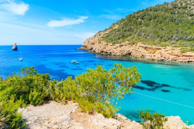İspanya 'nın İbiza adasında mavi deniz suyunda balıkçı teknesiyle Cala Benirras Körfezi manzarası