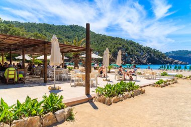 CALA BENIRRAS BEACH, IBIZA ADASI - 16 Mayıs 2017: İspanya 'nın İbiza adası Cala Benirras sahilindeki terasta restoran masalarında oturan insanlar.