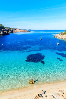 CALA SALADA BEACH, IBIZA ADASI - 17 Mayıs 2017: Adam İspanya 'nın İbiza adasındaki Cala Salada Koyu' nda, deniz suyunda duran genç bir kadının fotoğrafını çekiyor..