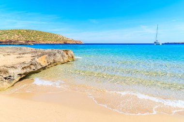 Güzel kumlu Cala Comte plajı ve denizdeki katamaran teknesi, İbiza Adası, İspanya