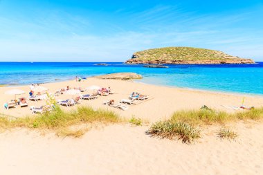 CALA COMTE BAY, IBIZA ADASI - 17 Mayıs 2017: Cala Comte plajında güneşlik ve şemsiyeler birçok turistin tatillerde dinlendiği İbiza Adası, İspanya.