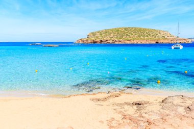 Cala Comte Körfezi 'nin güzel turkuaz suyu ve arka planda katamaran teknesi, İbiza Adası, İspanya