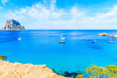 Cala d 'Hort Koyu' nun güzel mavi deniz suyundaki tekneleri ve İspanya 'nın İbiza adasındaki Es Vedra adası manzarası.