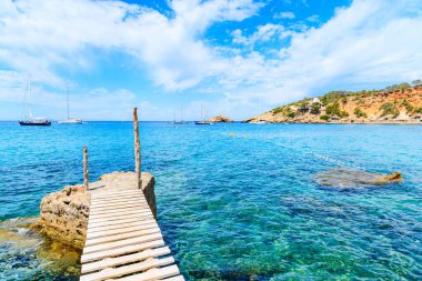 Cala d 'Hort körfezindeki küçük ahşap iskele ve Es Vedra Adası, İbiza Adası, İspanya manzarası.