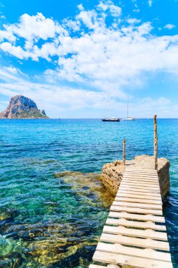 Cala d 'Hort körfezindeki küçük ahşap iskele ve Es Vedra Adası, İbiza Adası, İspanya manzarası.