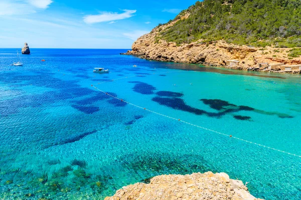 İspanya 'nın İbiza adasında mavi deniz suyunda balıkçı teknesiyle Cala Benirras Körfezi manzarası