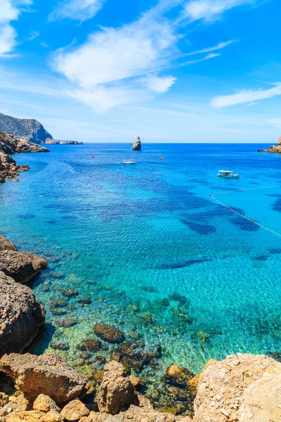 İspanya 'nın İbiza adasında mavi deniz suyunda tekneli Cala Benirras Körfezi manzarası