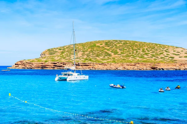 İspanya 'nın İbiza adasındaki Cala Comte Körfezi' nde mavi denizde katamaran teknesi.