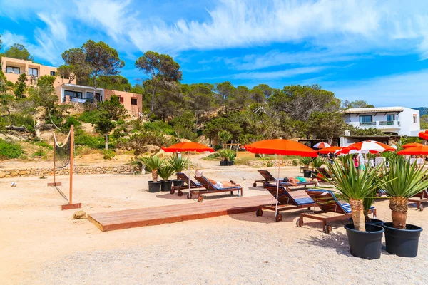 IBIZA Adaları, İspanya - 17 Mayıs 2017: İnsanlar İspanya 'nın İbiza adasındaki Cala Carbo Körfezi' nde güneşlik ve şemsiyelerle ahşap terasta dinleniyor.