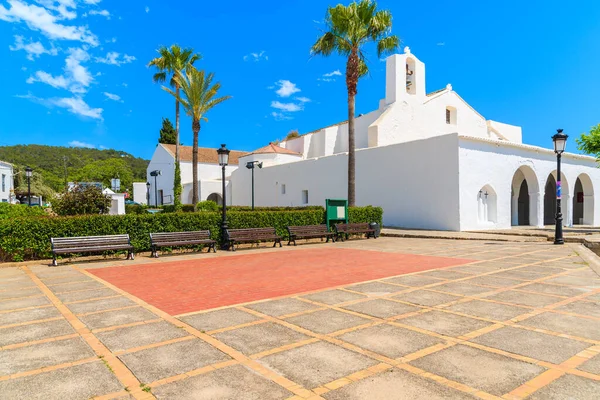 İspanya 'nın İbiza adasındaki Sant Carles de Peralta köyünde beyaz kilise ve palmiye ağaçları olan bir meydan.