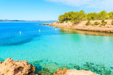 Sabahın erken saatlerinde kristal berrak deniz suyuyla güzel Cala Gracioneta Körfezi manzarası, İbiza Adası, İspanya