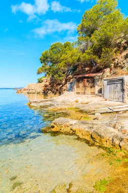 Sabahın erken saatlerinde İspanya 'nın İbiza adasında kıyıda kayıkhaneleri olan güzel Cala Gracio plajı manzarası.