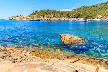 İspanya 'nın İbiza adasındaki Cala Salada Körfezi' nde mavi deniz suyunda yüzen tekneler.