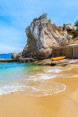 Sarı balıkçı teknesi ve Cala San Vicente Körfezi 'nde büyük bir kaya parçası, İbiza Adası, İspanya
