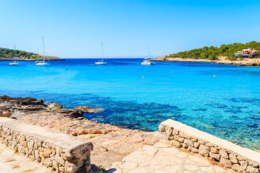 İspanya 'nın İbiza adasındaki Cala Portinatx Körfezi' ndeki mavi deniz boyunca uzanan kıyı şeridi manzarası