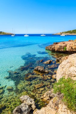 İspanya 'nın İbiza adasındaki Cala Portinatx Körfezi kıyısındaki turkuaz deniz suyundaki kayaların görüntüsü