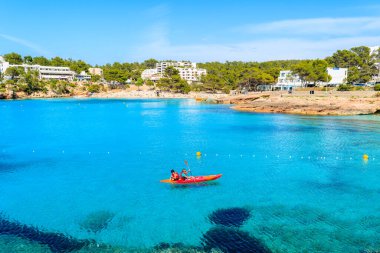 CALA PORTINATX BAY, IBIZA ADASI - 22 Mayıs 2017: İspanya 'nın İbiza adası Cala Portinatx Koyu' nun mavi deniz suyunda kano süren turistler.