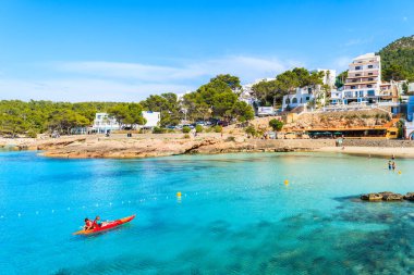 CALA PORTINATX BAY, IBIZA ADASI - 22 Mayıs 2017: İspanya 'nın İbiza adası Cala Portinatx Koyu' nun mavi deniz suyunda kano süren turistler.