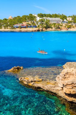 IBIZA Adaları, İspanya - 22 Mayıs 2017: İspanya 'nın İbiza adası Cala Portinatx Koyu' nun mavi deniz suyunda kano süren turistler.