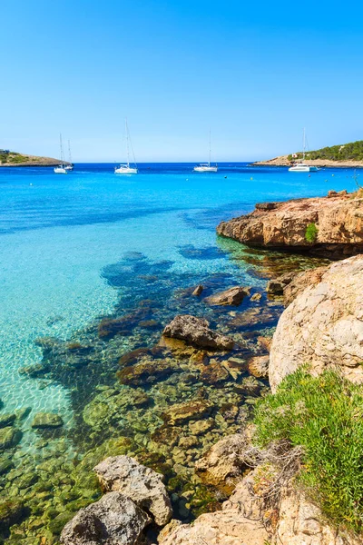 İspanya 'nın İbiza adasındaki Cala Portinatx Körfezi kıyısındaki turkuaz deniz suyundaki kayaların görüntüsü