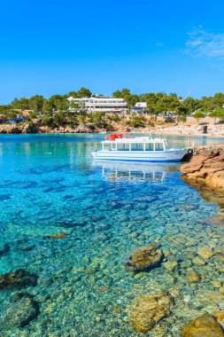 İspanya 'nın İbiza adasındaki Cala Portinatx Körfezi' nde demirleyen turistler için beyaz ve mavi feribot.